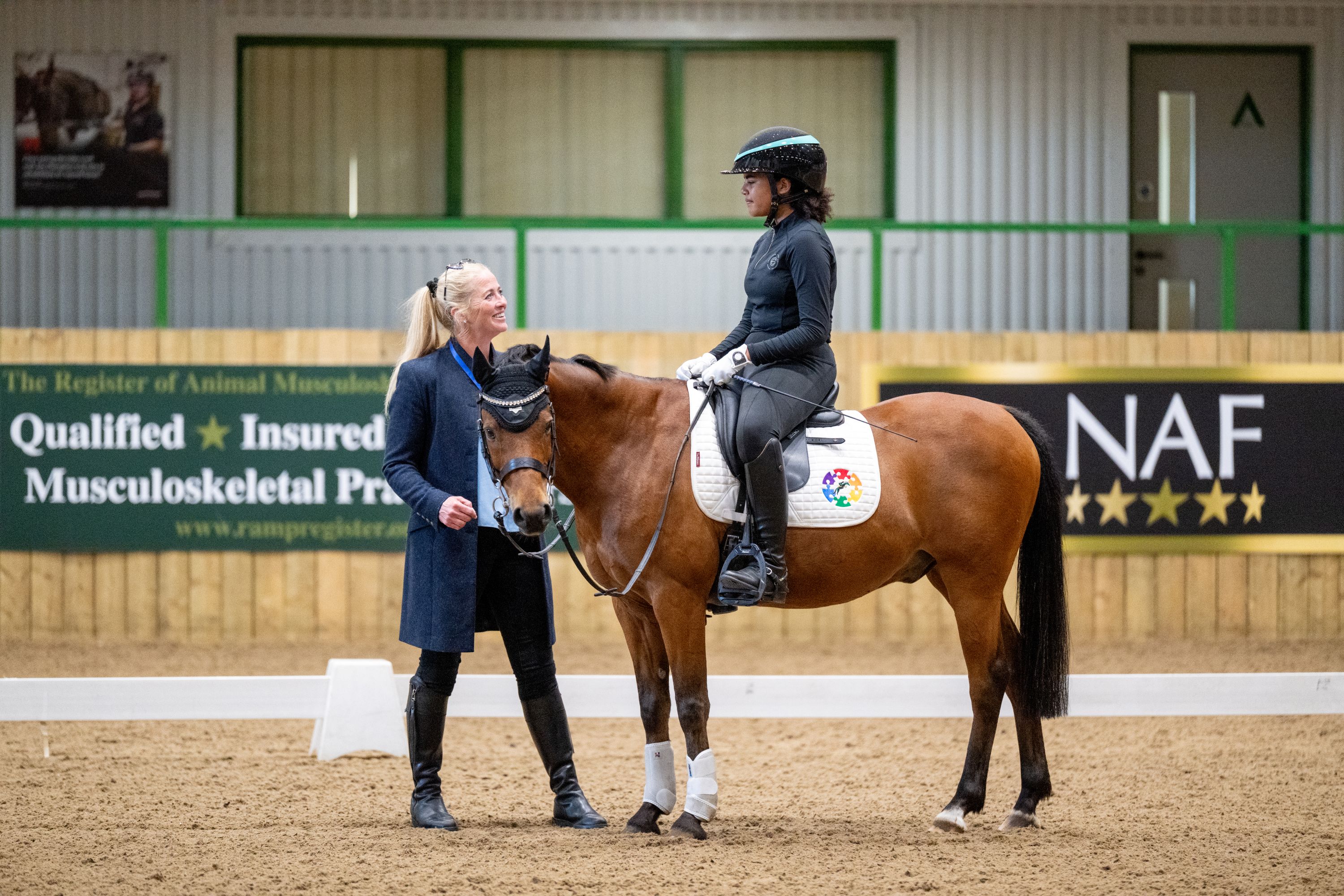 Rider with bay pony speaking to coach.